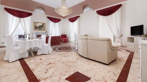 Een ruime woonkamer met een witte bank, een eettafel voor vier personen en een kroonluchter.