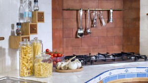Een keuken met pastajaren, tomaten, knoflook en hangend keukengerei.