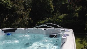 A hot tub with water jets, surrounded by greenery.