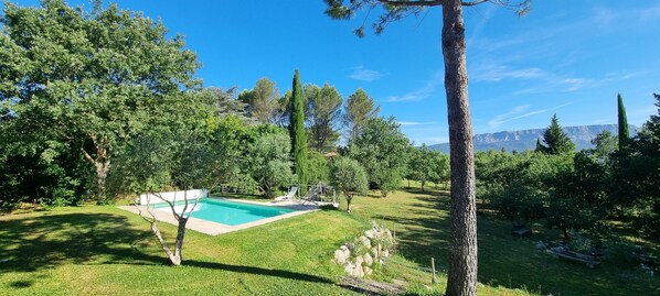 A backyard with a swimming pool, surrounded by trees and a mountain view. - Wooden house in a green setting (Fuveau)