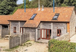 A rustic wooden cottage with a sloped roof, a wooden fence, and a stone wall.