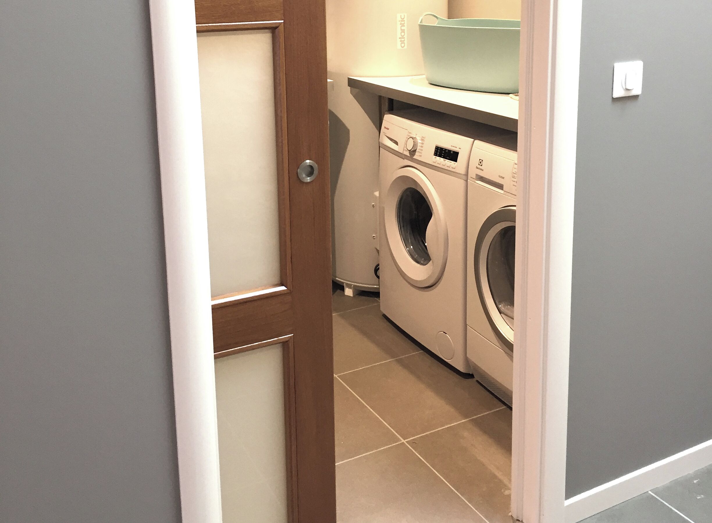 A laundry room with a washing machine and dryer, a door, and a light switch on the wall.