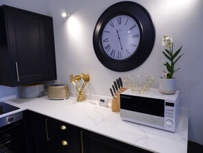 Enjoy cooking in this well-equipped kitchen with a wall-mounted clock, toaster, and knife block.