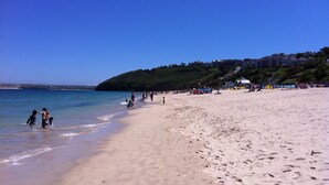 A sandy beach with footprints and a few people near the water. - Stunning Luxury Apartment In Carbis Bay, St Ives Close To The Beach with Parking (Carbis Bay, St Ives)