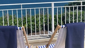A balcony with a view of the ocean, two chairs with towels, and a railing. - Stunning Luxury Apartment In Carbis Bay, St Ives Close To The Beach with Parking (Carbis Bay, St Ives)