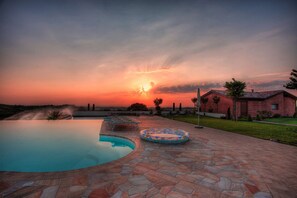 A swimming pool with a stone deck, a lounge chair, and a small inflatable pool.