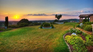 A well-maintained garden with a gazebo, a lawn, and a view of the sunset over a hilly landscape. - Le Orchidee Luxury Country Villa with pool just minutes from the Riviera (Roncofreddo)