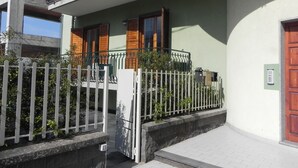A two-story building with a balcony, a white fence, and a wooden door.