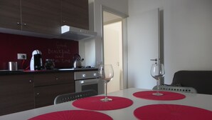 A modern kitchen with a white countertop, red placemats, and a kettle.