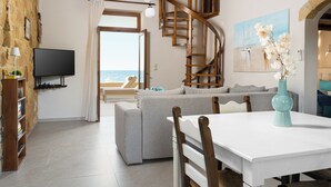 A living room with a sofa, a dining table, a TV, and a staircase.