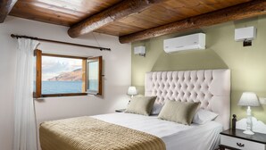 A bedroom with a large bed, a window with a view, and wooden beams on the ceiling.