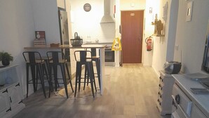 A modern kitchen with a dining area, wooden flooring, and a white table with remote controls. - Carvoeiro Travel, 100m from Carvoeiro Beach (Carvoeiro)