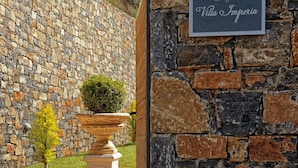 A stone wall with a sign reading "Villa Imperia" and a potted plant in front. - Villa Imperia 3 bedroom luxury villa - 200m from the beach (Elounda)