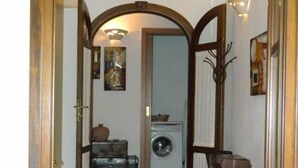 A hallway with a wooden archway leading to a laundry room. There is a washing machine, a table with a basket, and a chair. - HOUSE WITH VERANDA AT A FEW STEPS FROM THE SEA (Santa Maria Navarrese)