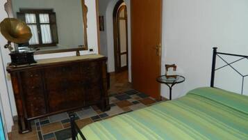 Een slaapkamer met een bed, een kaptafel, een spiegel en een deur naar een andere kamer.