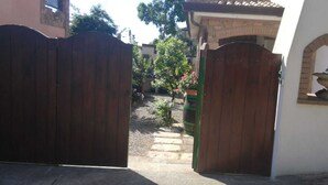 A gated entrance with a stone pathway leading to a building with a tiled roof and a brick wall. - HOUSE WITH VERANDA AT A FEW STEPS FROM THE SEA (Santa Maria Navarrese)