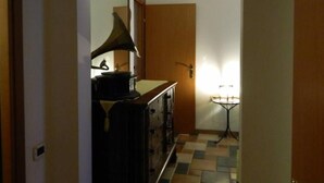 A narrow hallway with a wooden door at the end, a lamp on the floor, and a vintage gramophone on a cabinet. - HOUSE WITH VERANDA AT A FEW STEPS FROM THE SEA (Santa Maria Navarrese)