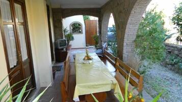 Un coin repas avec une table dressée pour deux personnes, des bancs et un téléviseur posé sur un meuble.