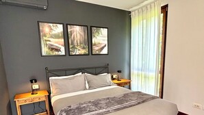Une chambre à coucher avec un lit, deux tables de chevet, une commode et une fenêtre avec des rideaux.