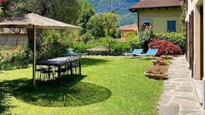 Un jardin bien entretenu, agrémenté d’une table et de chaises pour les repas, d’une pergola et offrant une vue sur les montagnes.