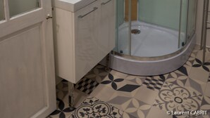 Ein modernes Badezimmer mit einer Glaskabine zur Dusche, einem weißen Waschbecken und einem Spiegel darüber.