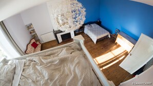 Ein Schlafzimmer mit Bett, Schreibtisch, Stuhl, Heizkörper und Bücherregal.