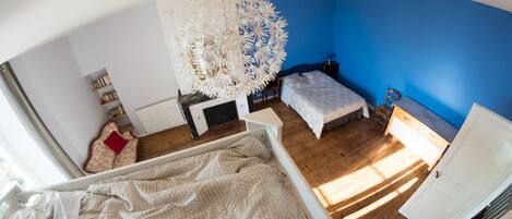 Een slaapkamer met een bed, een bureau, een stoel, een radiator en een boekenkast.