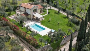 A two-story house with a swimming pool, surrounded by olive trees and a stone wall. - BEAUTIFUL VILLA WITH ALL THE COMFORTS  (malcesine)