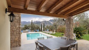 A covered patio with a pool, outdoor seating, and a view of mountains. - BEAUTIFUL VILLA WITH ALL THE COMFORTS  (malcesine)