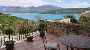 Ein Balkon mit Blumentöpfen, einer Steinmauer und einem Tisch mit Stühlen, beides mit Fliesen.