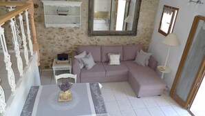 Ein Wohnzimmer mit Steinwand, einem rosafarbenen Sofa, einem Tisch mit einer Vase und einem Spiegel.