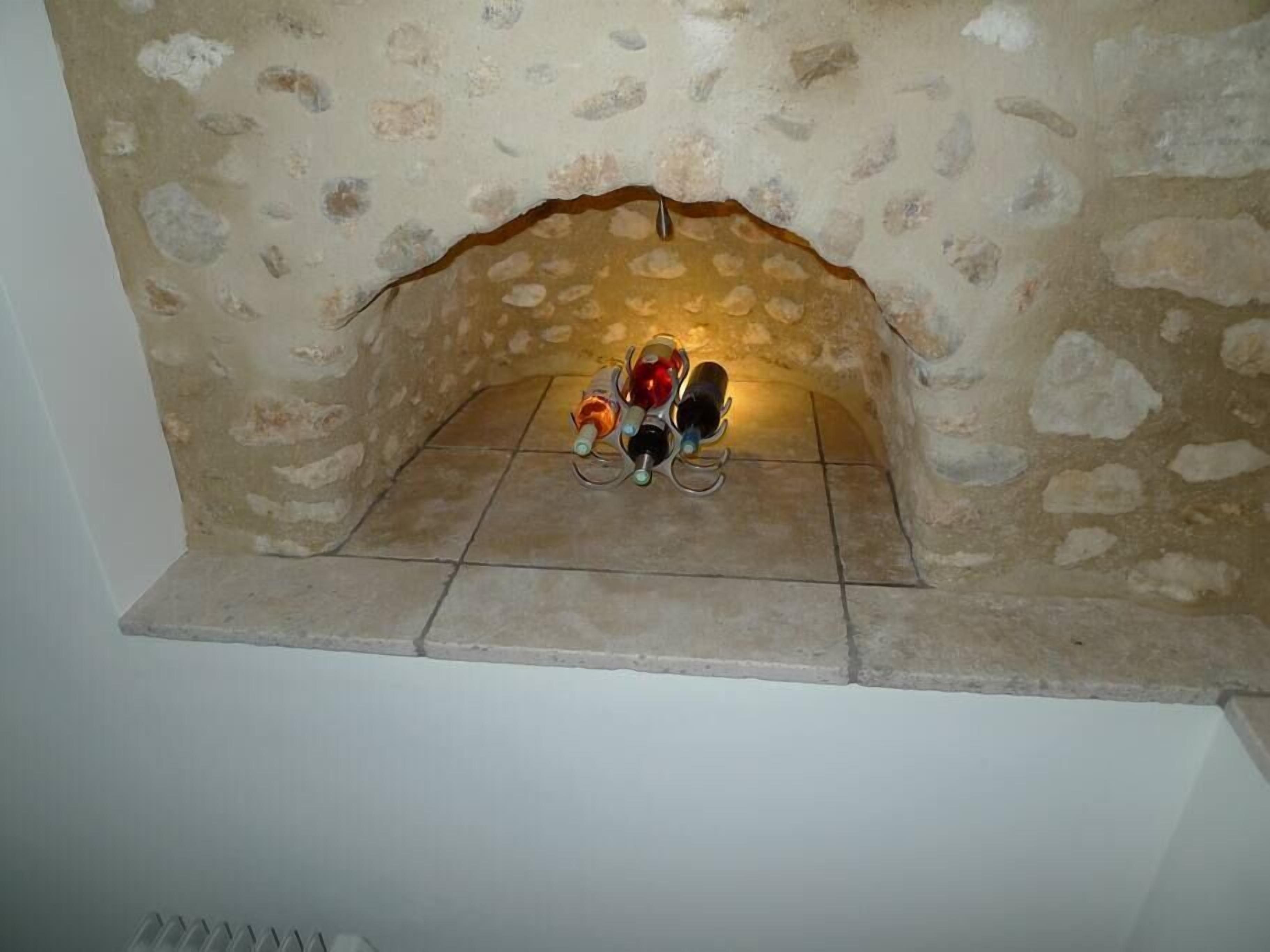A stone fireplace with three wine bottles placed on a shelf.