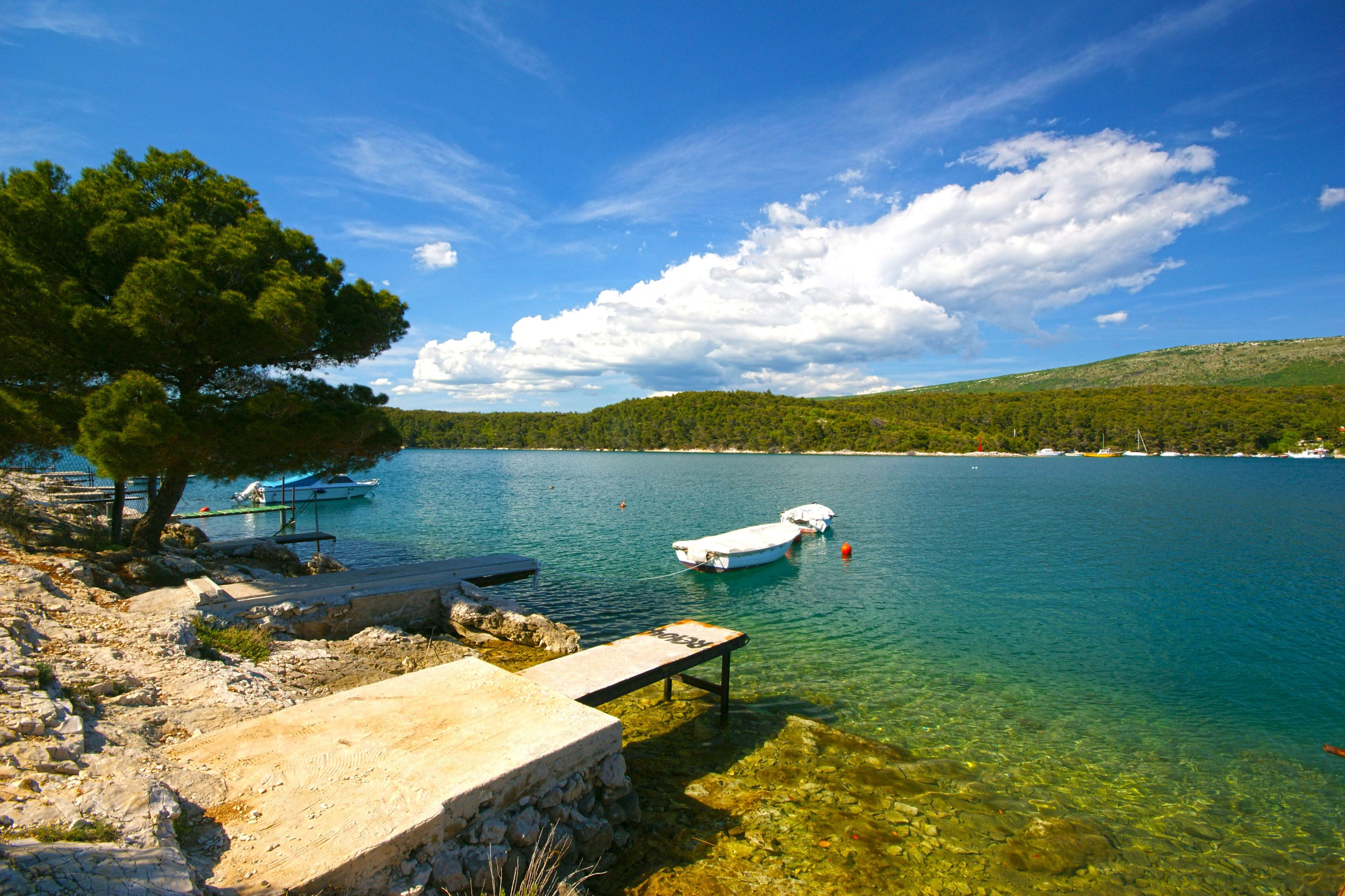 A clear lake with boats, a dock, and a stone platform.