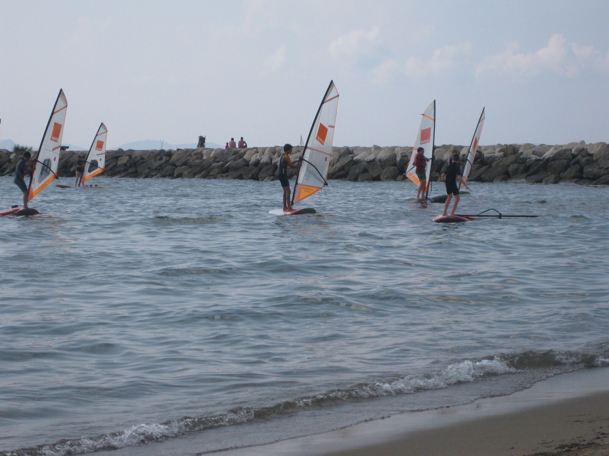 Una playa con gente practicando windsurf.