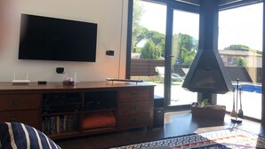 A modern living room with a flat-screen TV, a wooden entertainment unit, and a large sliding glass door leading to an outdoor area. - New villa with swimming pool in the Costa Brava. Now with WiFi! (Mas Ambros, Calonge)