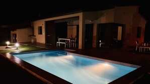 A rectangular swimming pool with a tiled edge, surrounded by a deck. There is a covered outdoor seating area with tables and chairs. - New villa with swimming pool in the Costa Brava. Now with WiFi! (Mas Ambros, Calonge)