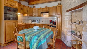Una cocina con gabinetes de madera, un refrigerador Bosch, un microondas y una cafetera.