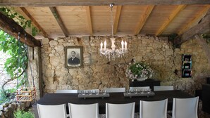 A stone-walled dining area with a wooden ceiling, a chandelier, and a framed portrait. - CHARMING VILLAGE HOUSE! near Bergerac StEmillion Bordeaux, heated pool jacuzzi (Saint-Martin-De-Gurson)