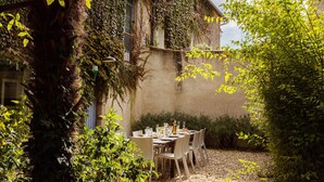 An outdoor dining area with a table set for four, surrounded by chairs, against a building with ivy-covered walls. - CHARMING VILLAGE HOUSE! near Bergerac StEmillion Bordeaux, heated pool jacuzzi (Saint-Martin-De-Gurson)