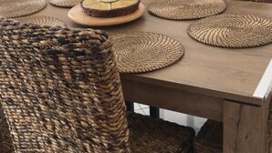 A dining area with a wooden table and woven chairs, a television, and a fireplace in the background. - Villa with SEA VIEW, 1 km from the BEACH and CITY CENTER, BBQ, TENNIS (Fréjus)
