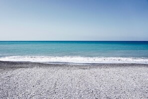Ein Strand mit Kiesküste und ruhigem türkisblauem Wasser.