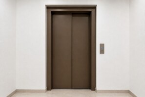 A closed elevator door in a hallway with a light switch on the wall.