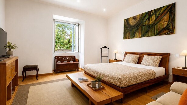 Ein Schlafzimmer mit Bett, Nachttischen, Schreibtisch, Stuhl, Fenster und einem Bild an der Wand.