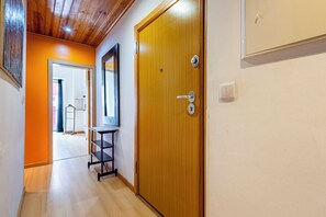 A hallway with a wooden door, a mirror, and a shelf.