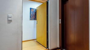Ein Flur mit Holzboden, einer Tür in Braun und einem an der Wand befestigten Lichtschalter.