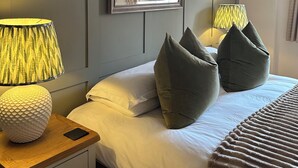 Ein Schlafzimmer mit einem Bett, zwei Nachttischlampen, einem Spiegel und einem Nachttisch aus Holz mit einem Telefon.