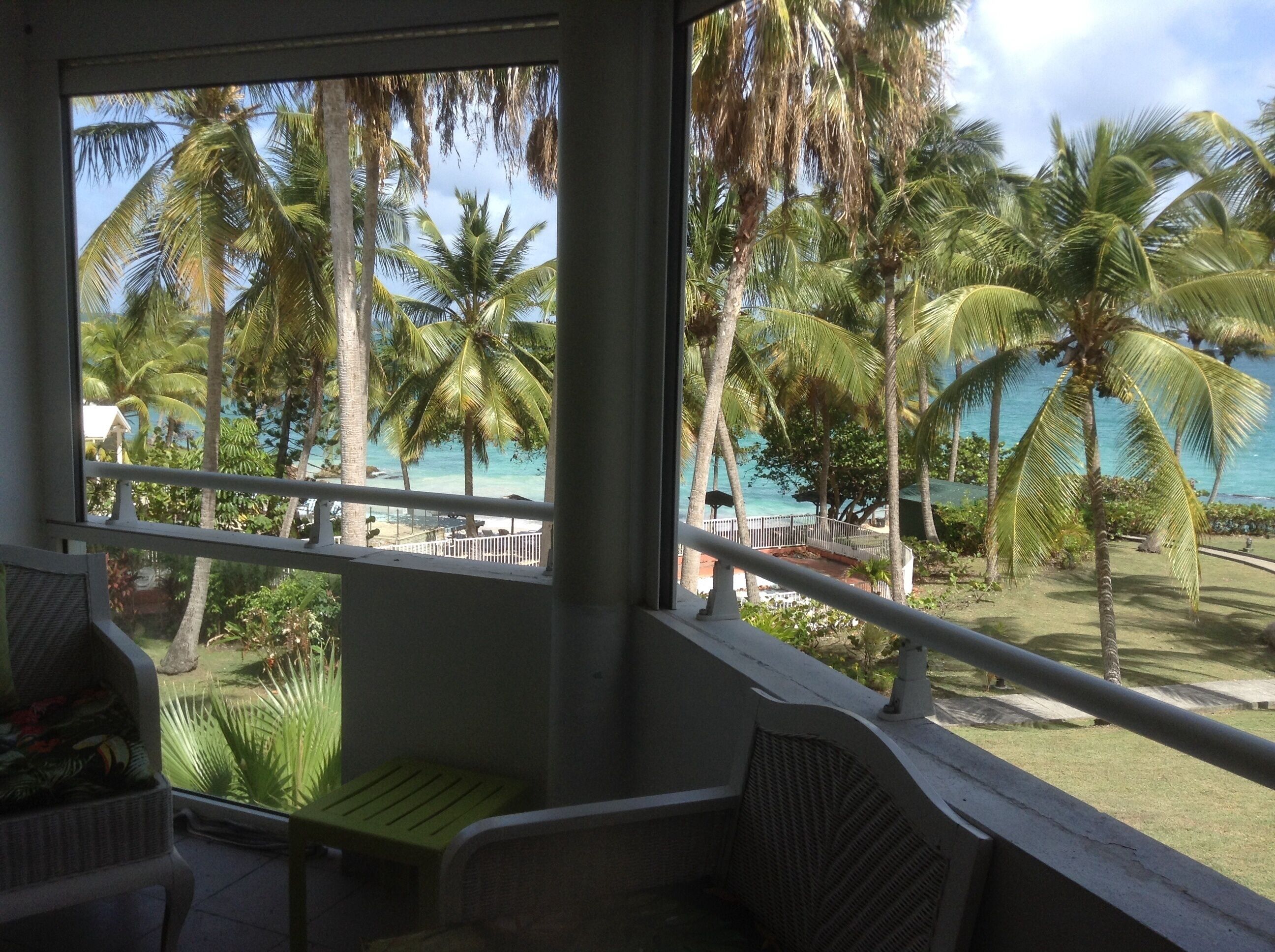 A balcony with a view of a beach and palm trees.