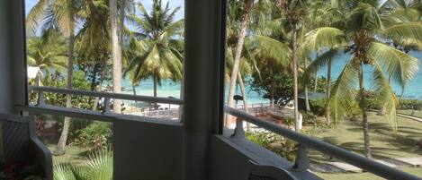 A balcony with a view of a beach and palm trees.