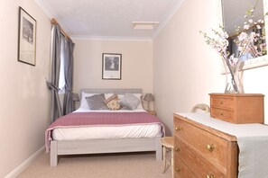 A bedroom with a bed, a dresser, a mirror, and two framed pictures on the wall. - Great location - sleeps up to five guests, just moments from the beach and town (Eastbourne)