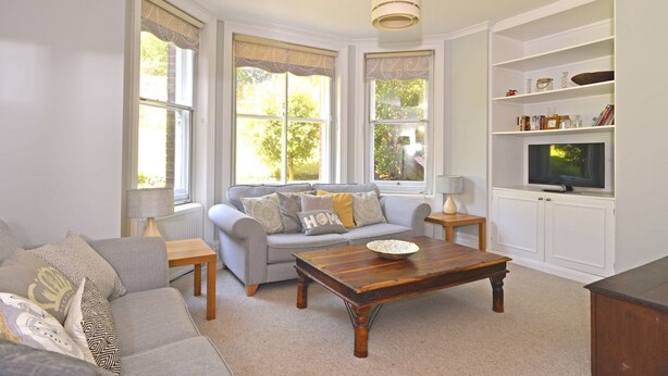 A living room with a sofa, coffee table, and TV stand. - Great location - sleeps up to five guests, just moments from the beach and town (Eastbourne)